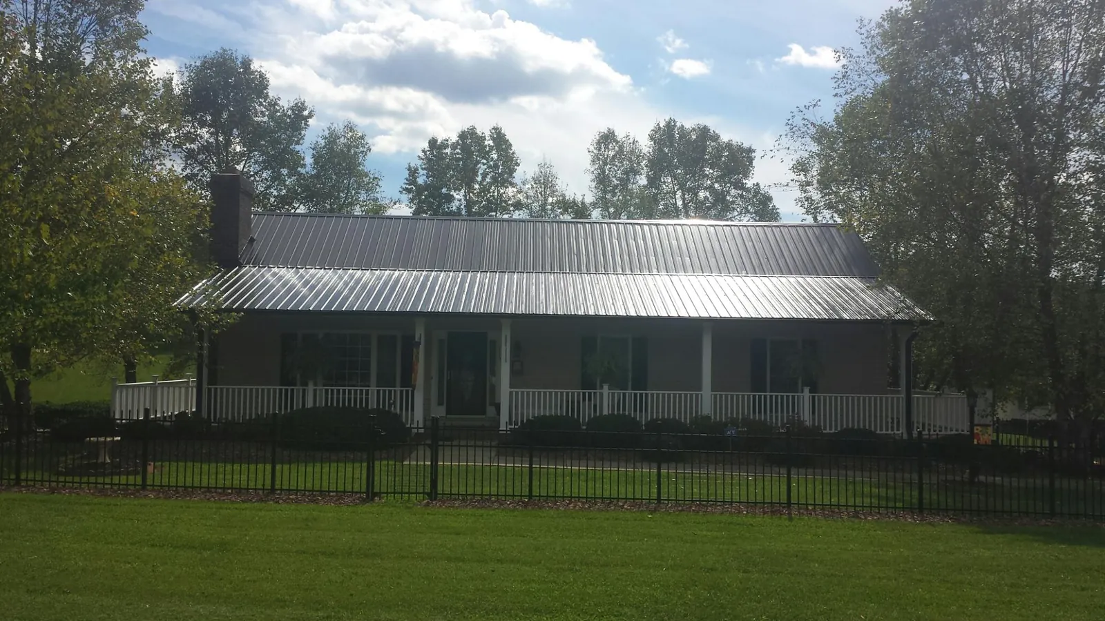 Gray metal roof on a brick ranch with a full width front porch — Gutter Guard Installation work by our crew in Cleveland