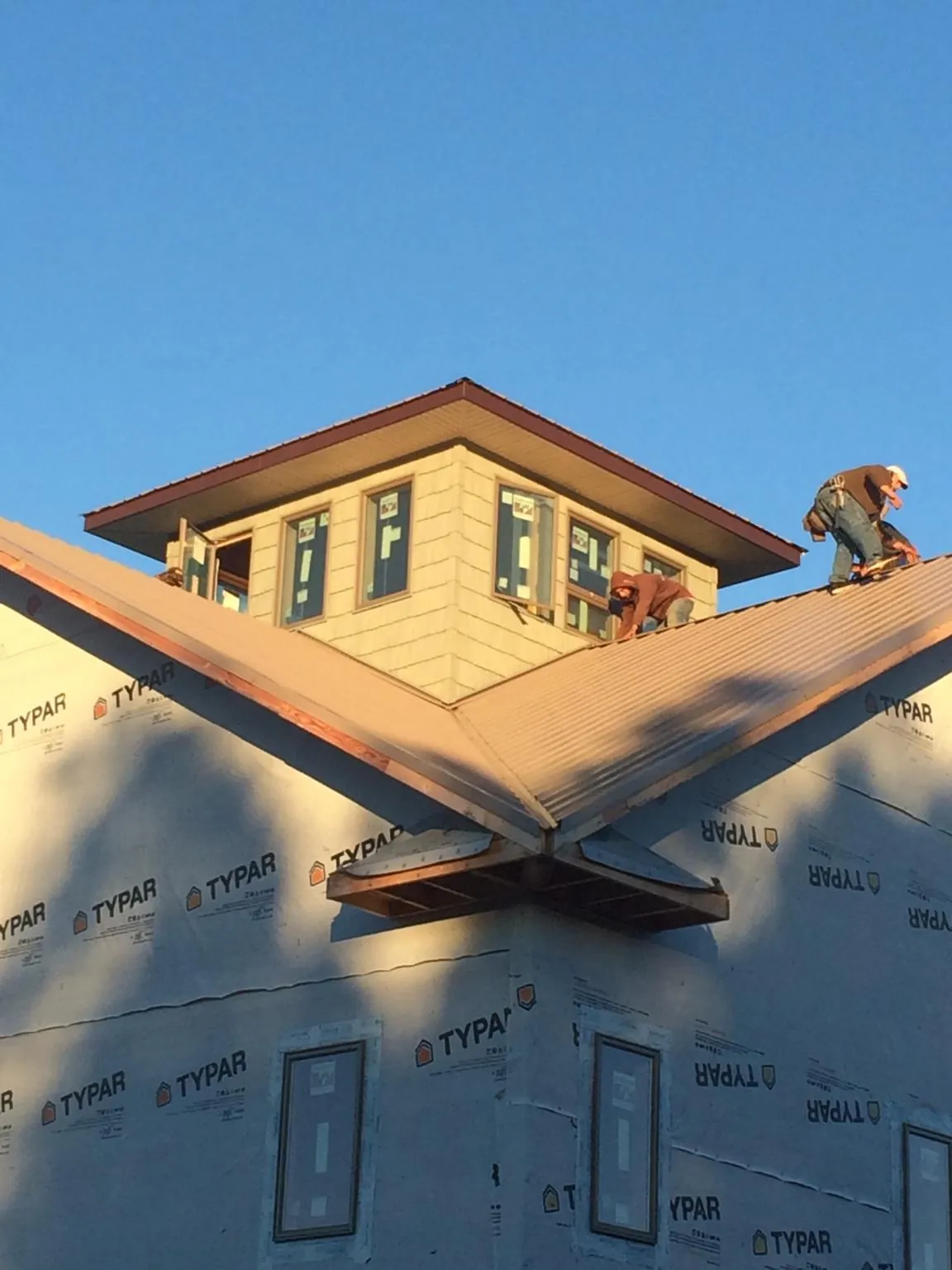 Roofers working around a rooftop cupola on a new metal roof at sunset — Roof Waterproofing in Cleveland by Roofing Brothers